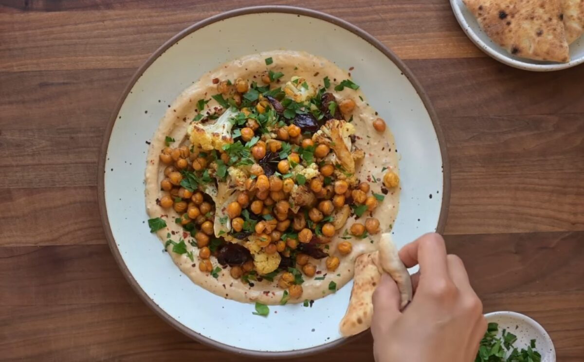 One of two vegan sheet pan dinners on a plate. This one includes roasted cauliflower, chickpeas, and Medjool dates on a base of whipped tahini