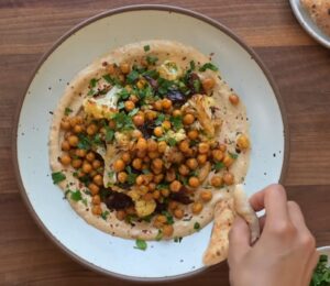 One of two vegan sheet pan dinners on a plate. This one includes roasted cauliflower, chickpeas, and Medjool dates on a base of whipped tahini