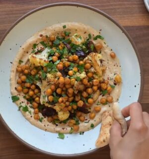 One of two vegan sheet pan dinners on a plate. This one includes roasted cauliflower, chickpeas, and Medjool dates on a base of whipped tahini