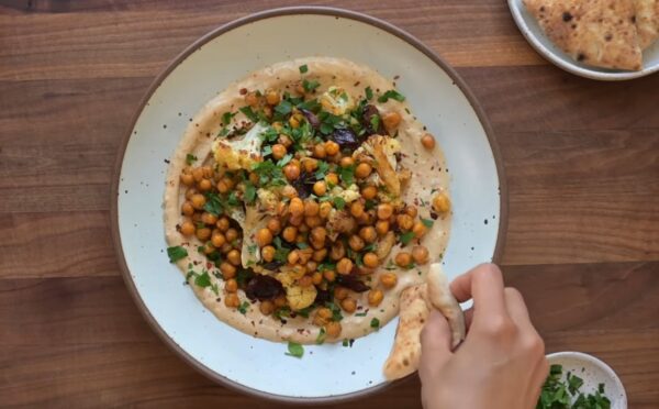 One of two vegan sheet pan dinners on a plate. This one includes roasted cauliflower, chickpeas, and Medjool dates on a base of whipped tahini