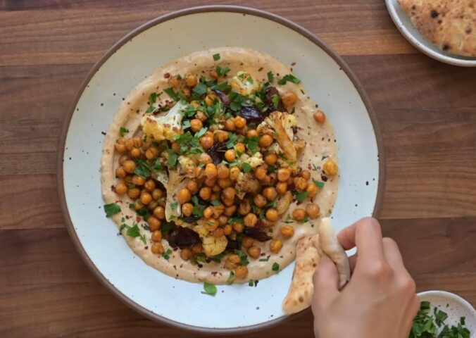 One of two vegan sheet pan dinners on a plate. This one includes roasted cauliflower, chickpeas, and Medjool dates on a base of whipped tahini