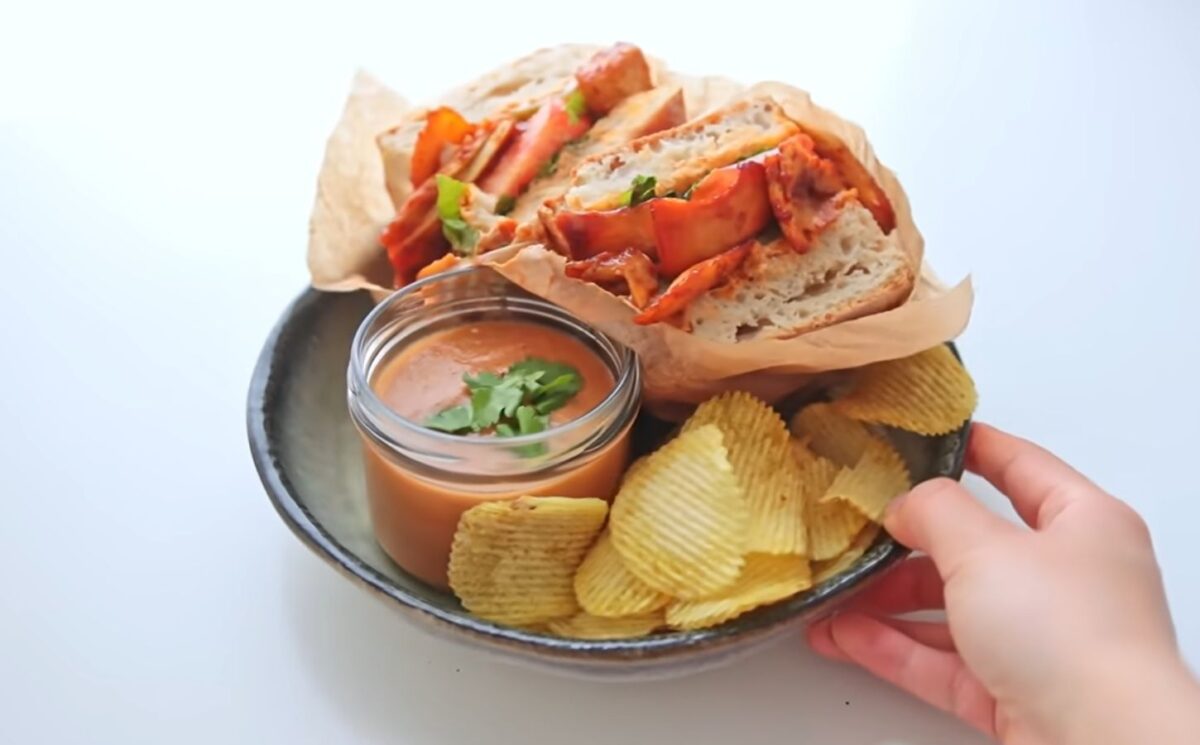 Plate with a chipotle BBQ tofu and mushroom sandwich, a bowl of gazpacho, and a side of chips, two out of Rome's six quick vegan summer meals