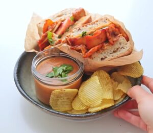 Plate with a chipotle BBQ tofu and mushroom sandwich, a bowl of gazpacho, and a side of chips, two out of Rome's six quick vegan summer meals