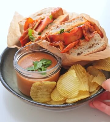 Plate with a chipotle BBQ tofu and mushroom sandwich, a bowl of gazpacho, and a side of chips, two out of Rome's six quick vegan summer meals