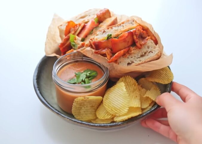 Plate with a chipotle BBQ tofu and mushroom sandwich, a bowl of gazpacho, and a side of chips, two out of Rome's six quick vegan summer meals