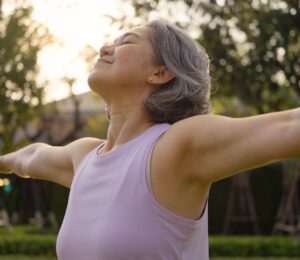 Middle-aged woman practicing yoga in a park, looking happy and inspired, to illustrate article about gut health during perimenopause