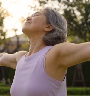 Middle-aged woman practicing yoga in a park, looking happy and inspired, to illustrate article about gut health during perimenopause