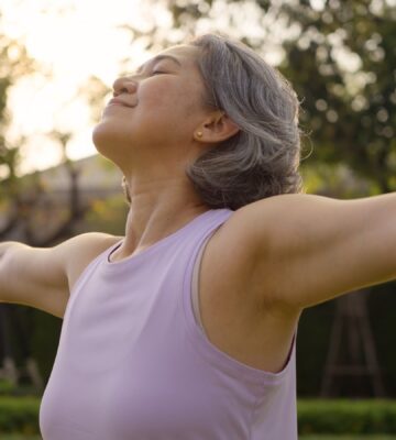 Middle-aged woman practicing yoga in a park, looking happy and inspired, to illustrate article about gut health during perimenopause