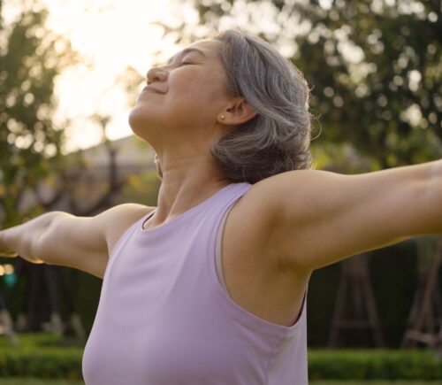Middle-aged woman practicing yoga in a park, looking happy and inspired, to illustrate article about gut health during perimenopause