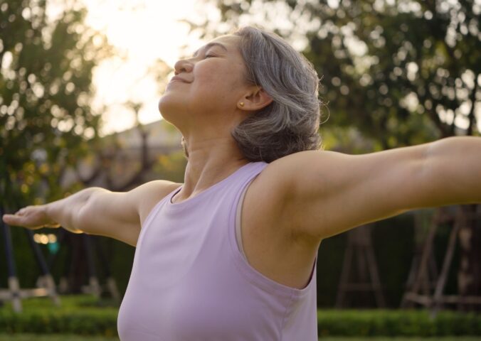 Middle-aged woman practicing yoga in a park, looking happy and inspired, to illustrate article about gut health during perimenopause