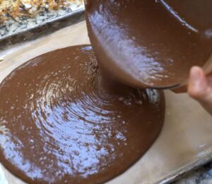Schinner pours the cake batter, made using her vegan chocolate cake mix, from a bowl onto a baking tray