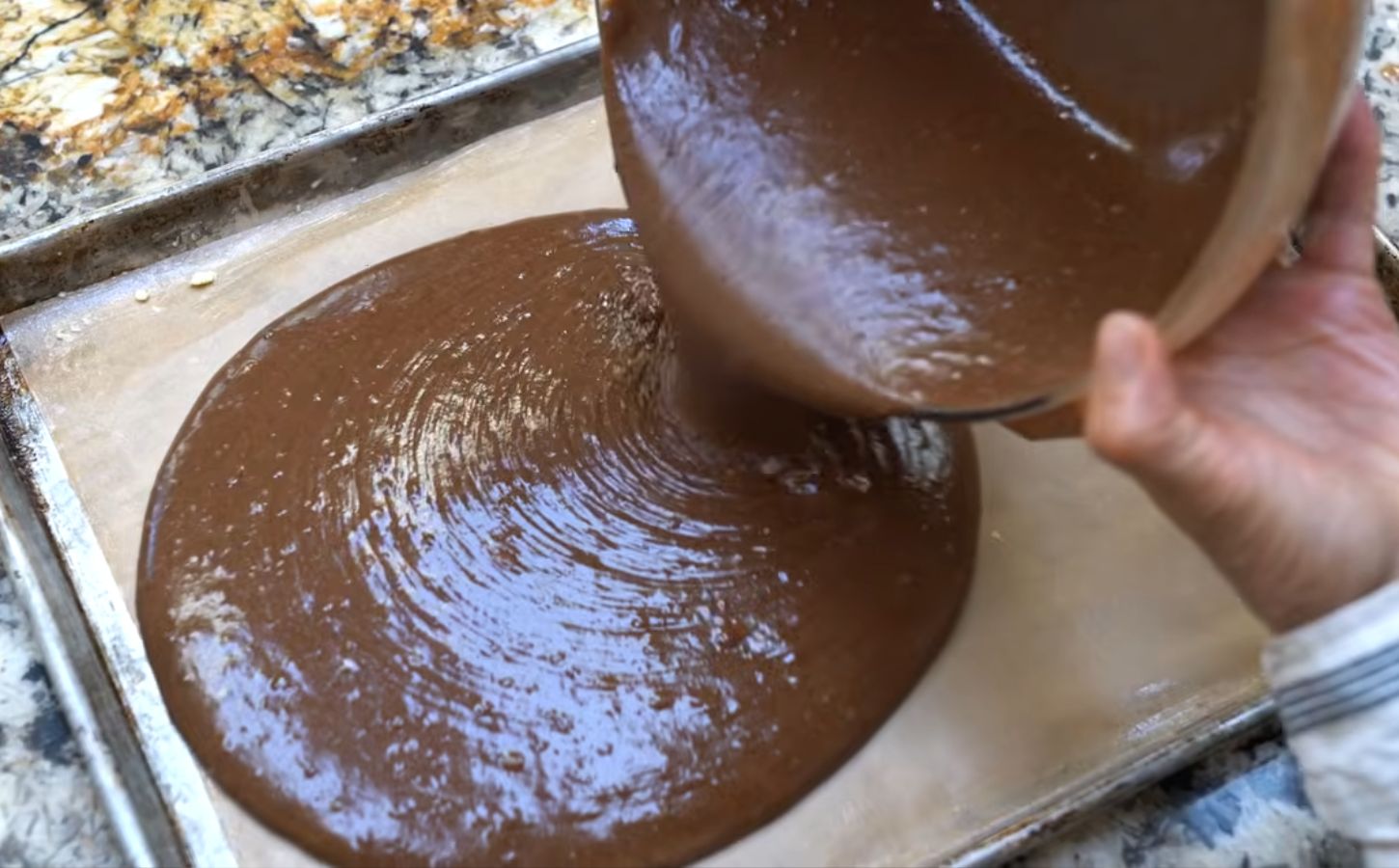 Schinner pours the cake batter, made using her vegan chocolate cake mix, from a bowl onto a baking tray
