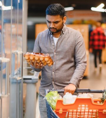 Photo shows a young man looking at a large box of eggs in the supermarket. According to a new poll, nearly three quarters of British shoppers incorrectly believe that farmed chickens are no longer caged