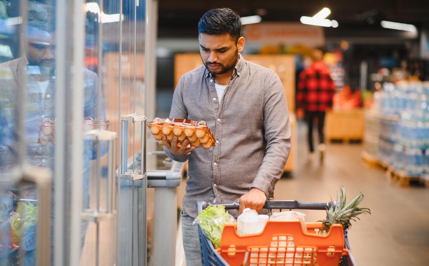 Photo shows a young man looking at a large box of eggs in the supermarket. According to a new poll, nearly three quarters of British shoppers incorrectly believe that farmed chickens are no longer caged