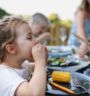 Photo shows a little girl eating corn on the cob and vegetables at a family BBQ. A new study has found that children and teenagers are more open to meat-free diets than adults, but can struggle to maintain them