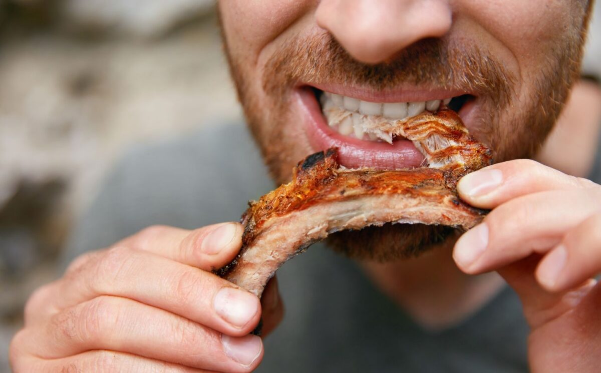 Photo shows a man eating a piece of meat off the bone. A new meta-research review has found that research backed by the animal agriculture industry is more likely to say that meat is beneficial