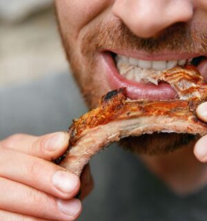 Photo shows a man eating a piece of meat off the bone. A new meta-research review has found that research backed by the animal agriculture industry is more likely to say that meat is beneficial