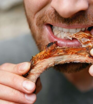 Photo shows a man eating a piece of meat off the bone. A new meta-research review has found that research backed by the animal agriculture industry is more likely to say that meat is beneficial
