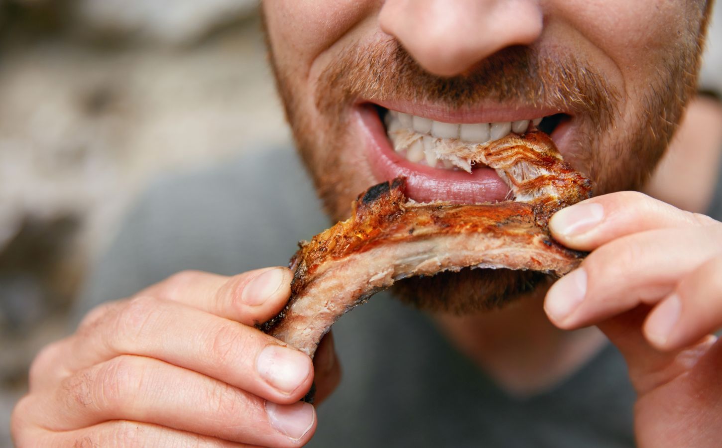 Photo shows a man eating a piece of meat off the bone. A new meta-research review has found that research backed by the animal agriculture industry is more likely to say that meat is beneficial