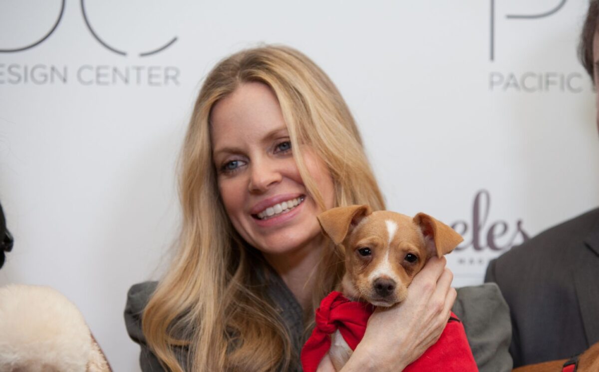Photo shows vegan actor Kristin Bauer holding up a dog at an event