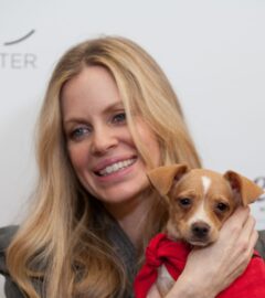 Photo shows vegan actor Kristin Bauer holding up a dog at an event