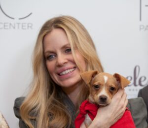 Photo shows vegan actor Kristin Bauer holding up a dog at an event