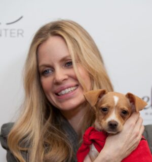 Photo shows vegan actor Kristin Bauer holding up a dog at an event