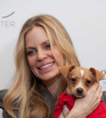 Photo shows vegan actor Kristin Bauer holding up a dog at an event