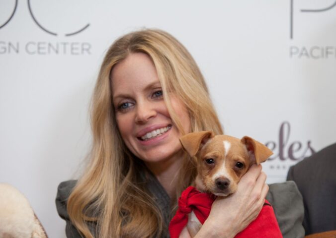 Photo shows vegan actor Kristin Bauer holding up a dog at an event