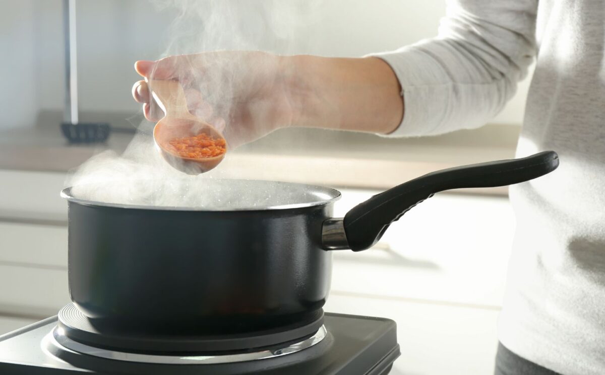 Photo shows a woman's hand as she cooks red lentils in a saucepan. The Netherlands has reduced its national meat recommendations for omnivores by at least 40 percent