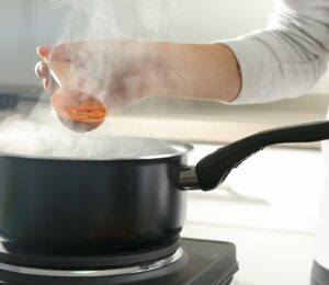 Photo shows a woman's hand as she cooks red lentils in a saucepan. The Netherlands has reduced its national meat recommendations for omnivores by at least 40 percent