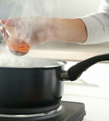 Photo shows a woman's hand as she cooks red lentils in a saucepan. The Netherlands has reduced its national meat recommendations for omnivores by at least 40 percent