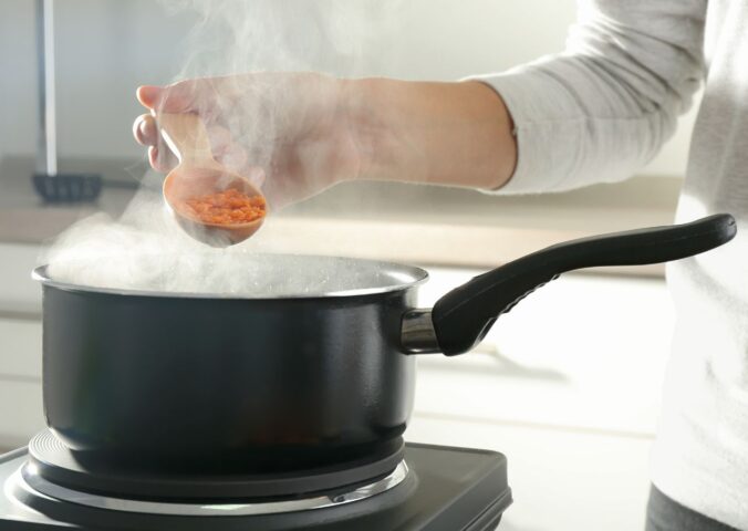 Photo shows a woman's hand as she cooks red lentils in a saucepan. The Netherlands has reduced its national meat recommendations for omnivores by at least 40 percent