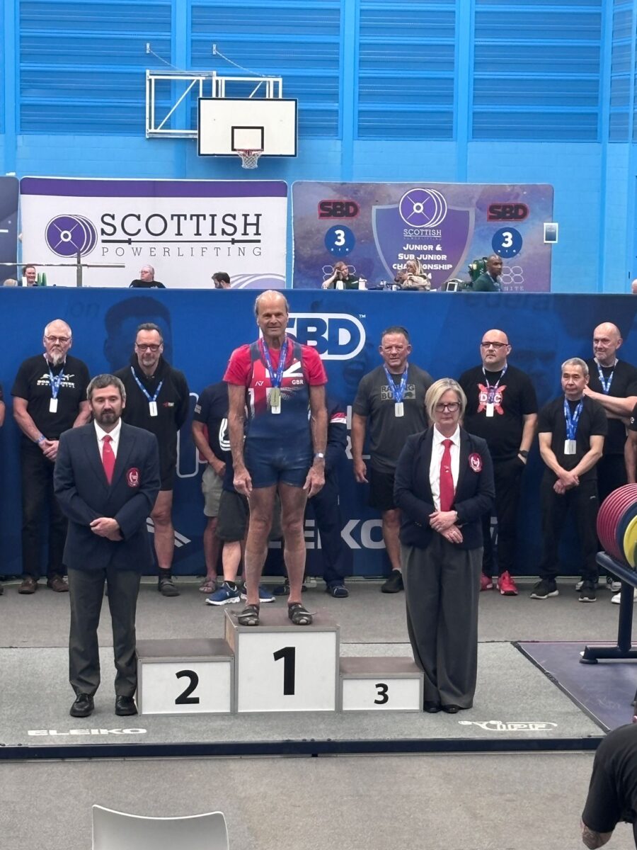 Photo shows Dr Doug Graham, a raw vegan fitness coach and champion powerlifter, standing on the first place podium at an event.