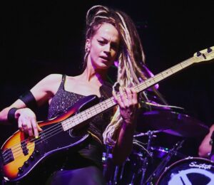Photo shows vegan rock star Tanya O'Callaghan, who was recently interviewed by Plant Based News, playing bass onstage