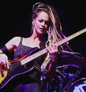 Photo shows vegan rock star Tanya O'Callaghan, who was recently interviewed by Plant Based News, playing bass onstage
