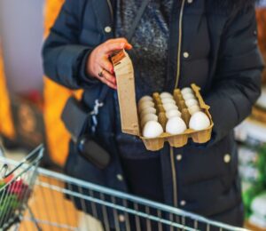 Photo shows a woman shopping in a supermarket with a trolley and holding a large, open box of eggs. According to a new survey, many US adults incorrectly believe that chicken, beef, and eggs reduce high cholesterol risk