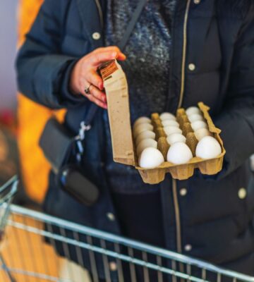 Photo shows a woman shopping in a supermarket with a trolley and holding a large, open box of eggs. According to a new survey, many US adults incorrectly believe that chicken, beef, and eggs reduce high cholesterol risk