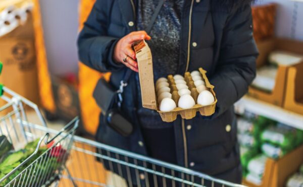 Photo shows a woman shopping in a supermarket with a trolley and holding a large, open box of eggs. According to a new survey, many US adults incorrectly believe that chicken, beef, and eggs reduce high cholesterol risk