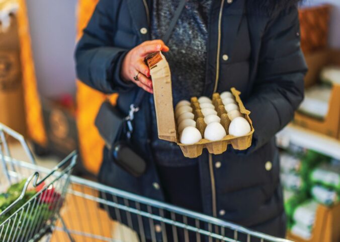 Photo shows a woman shopping in a supermarket with a trolley and holding a large, open box of eggs. According to a new survey, many US adults incorrectly believe that chicken, beef, and eggs reduce high cholesterol risk