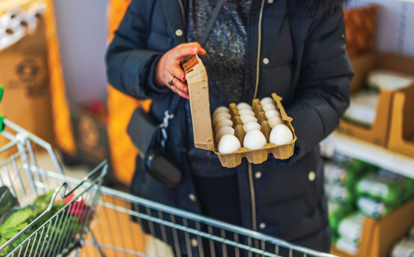 Photo shows a woman shopping in a supermarket with a trolley and holding a large, open box of eggs. According to a new survey, many US adults incorrectly believe that chicken, beef, and eggs reduce high cholesterol risk