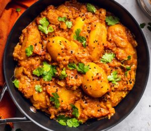 Vegan Dum Aloo with baby potatoes, tomato gravy, fresh spices, and turmeric
