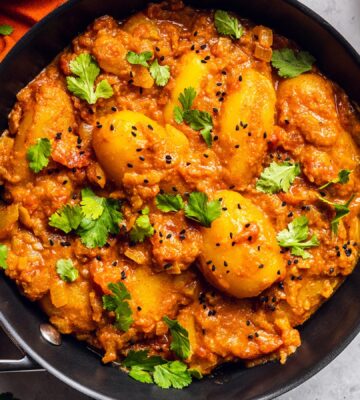 Vegan Dum Aloo with baby potatoes, tomato gravy, fresh spices, and turmeric
