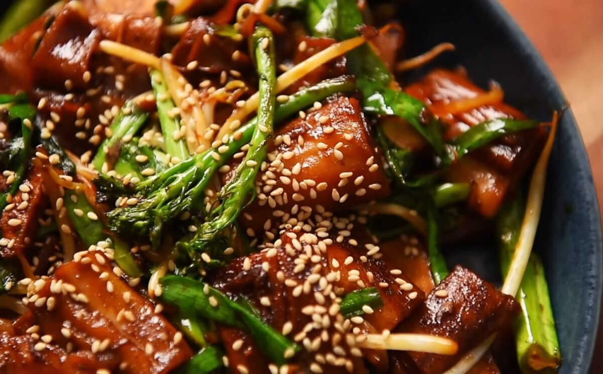 A plate of pan-fried cheung fun with smoked tofu, broccolini, garlic chives, bean sprouts and white sesame seeds, one of Wil Yeung's Chinese-style vegan recipes