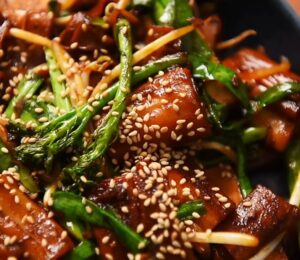 A plate of pan-fried cheung fun with smoked tofu, broccolini, garlic chives, bean sprouts and white sesame seeds, one of Wil Yeung's Chinese-style vegan recipes