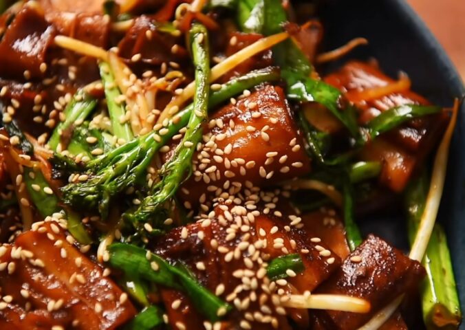 A plate of pan-fried cheung fun with smoked tofu, broccolini, garlic chives, bean sprouts and white sesame seeds, one of Wil Yeung's Chinese-style vegan recipes