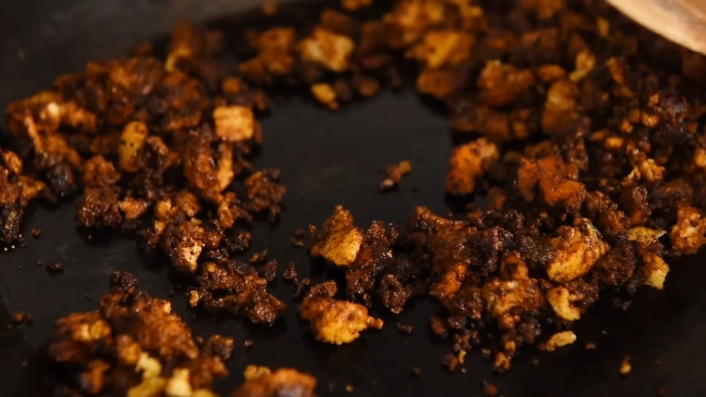 Image of the crumbled extra-firm tofu sautéed in a nonstick pan with chili oil and dark soy sauce for one of Yeung's Chinese-style vegan recipes.