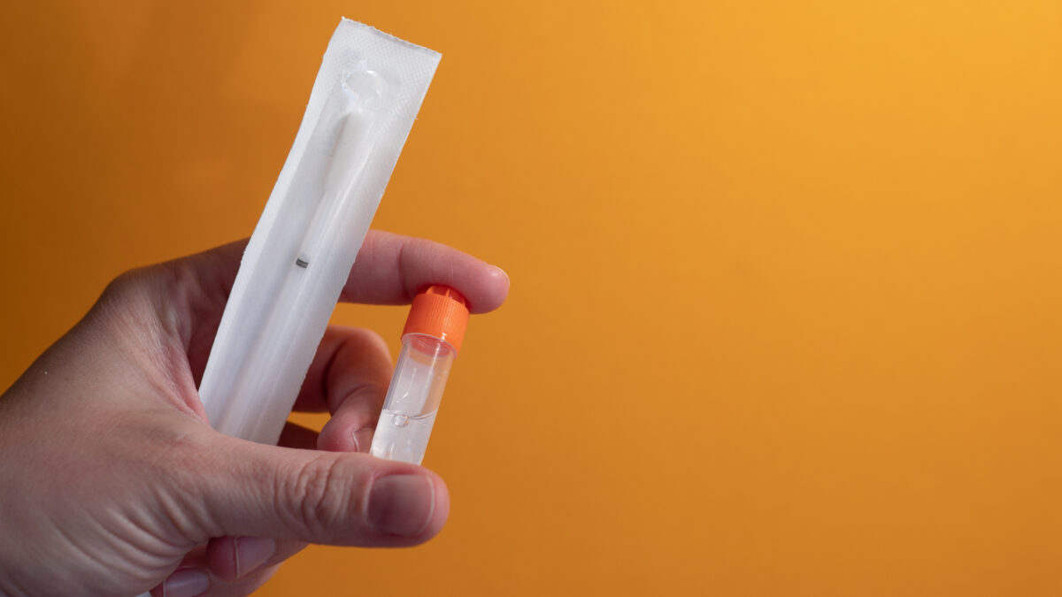 Photo shows a hand holding a at-home DNA or genetic testing kit. These types of tests, and specifically their use to create personalized diet plans, supplement packages, and exercise regimes, are not supported by clinical evidence.