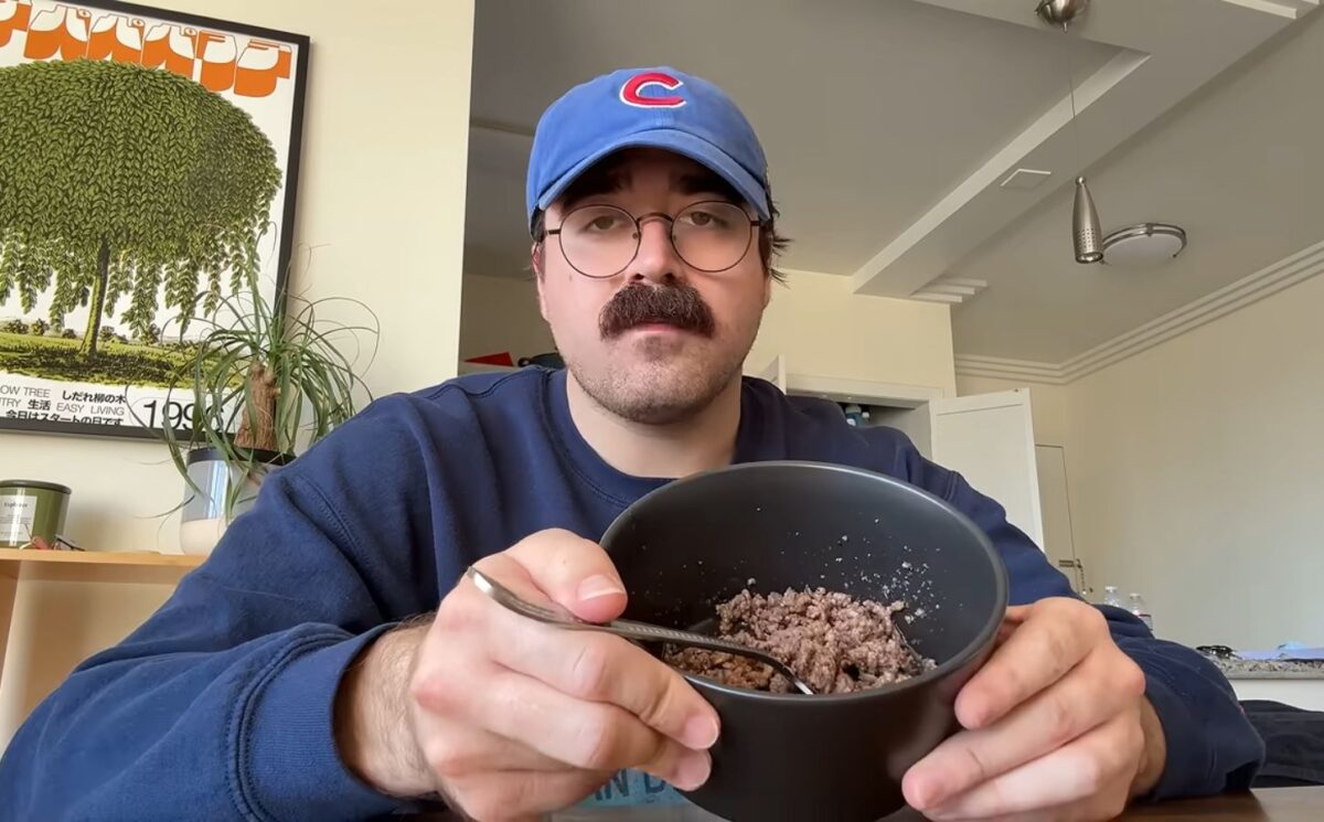 During Eddy Burback's carnivore diet experiment he sits at a table in his apartment holding a bowl of ground beef toward the camera