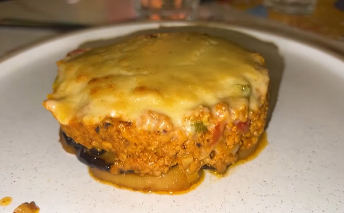 A plate of vegan moussaka topped with plant-based cheese served during a vegan food tour of Greece in Athens.